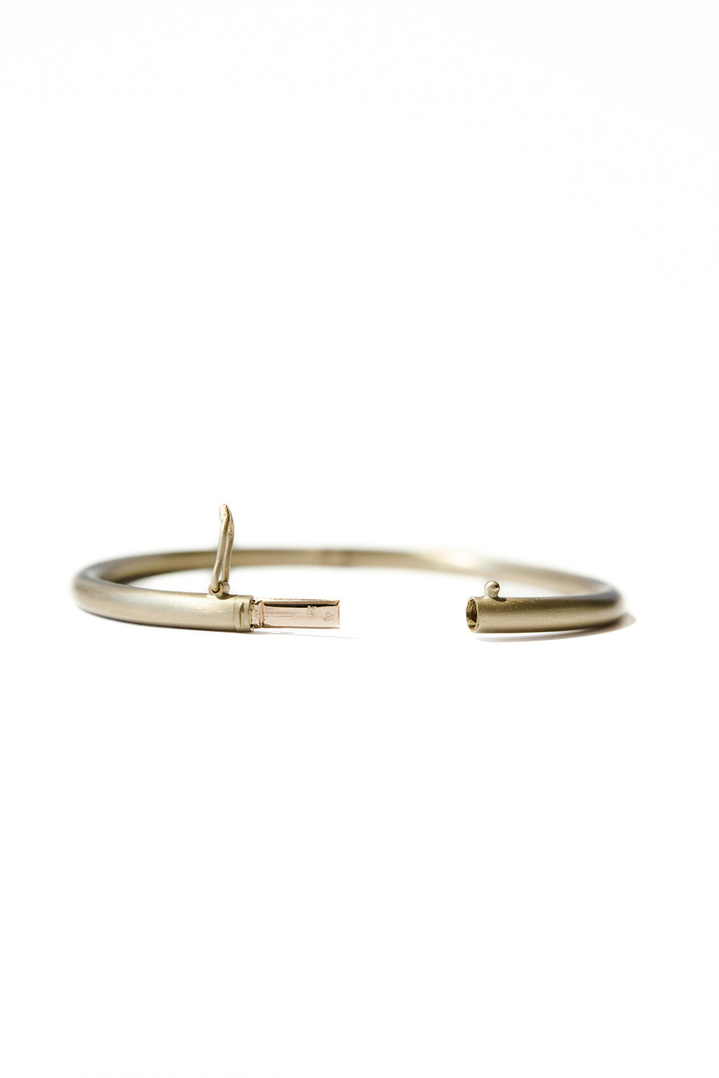 Opened gold oval bracelet with matte finish on white background