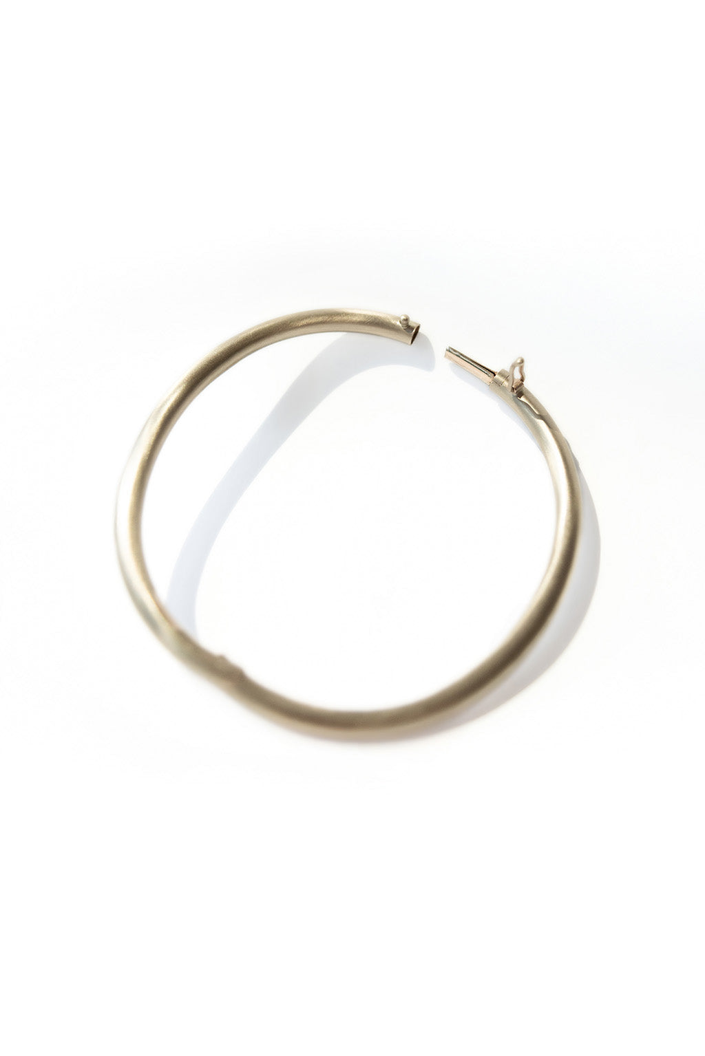 Gold oval bracelet with matte finish on white background