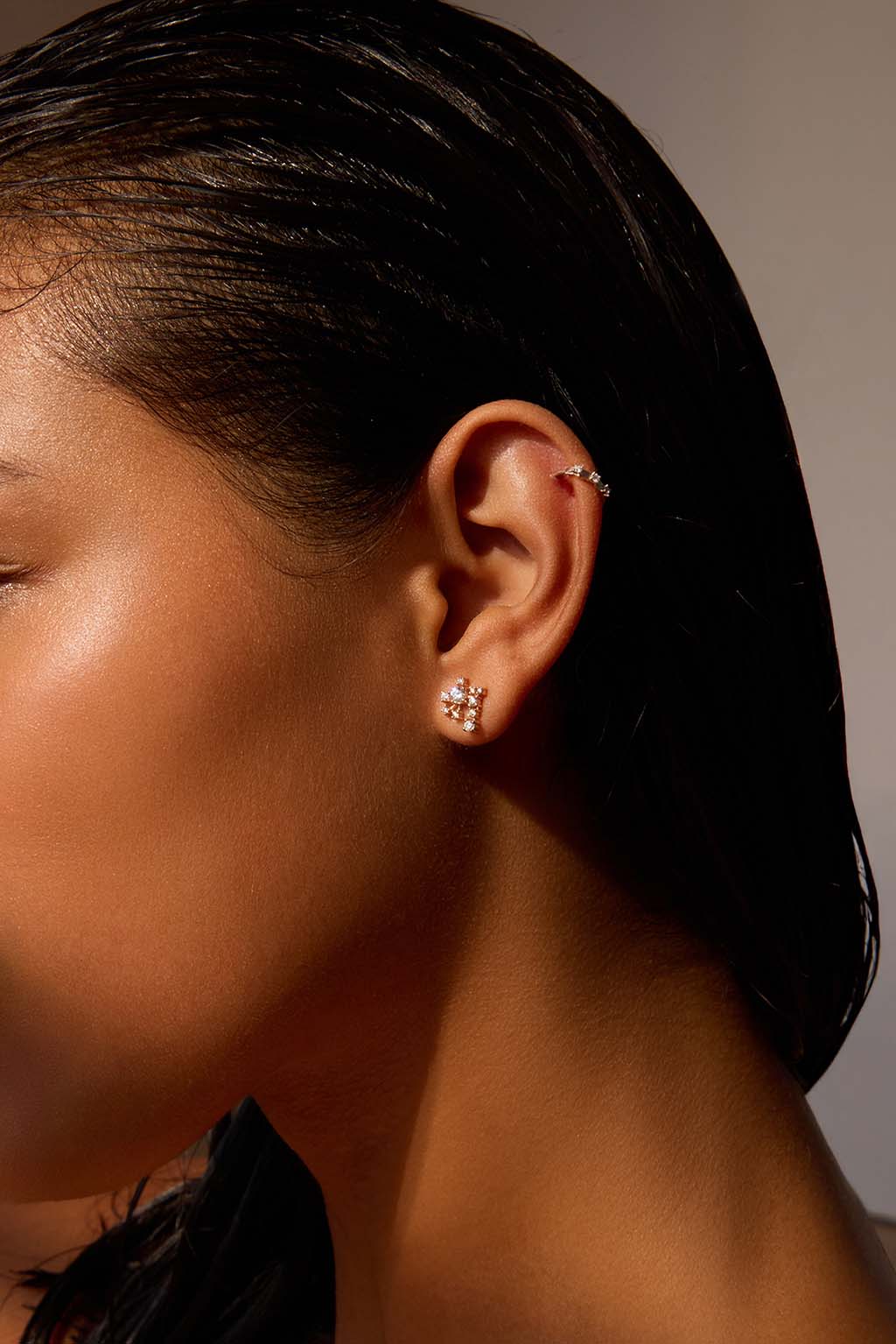Model wearing the Star Cascade earring in 18k gold. A compact, asymmetrical cluster of diamonds sits close to the earlobe, catching the light like a suspended, luminous cascade. Delicate and easy to wear.