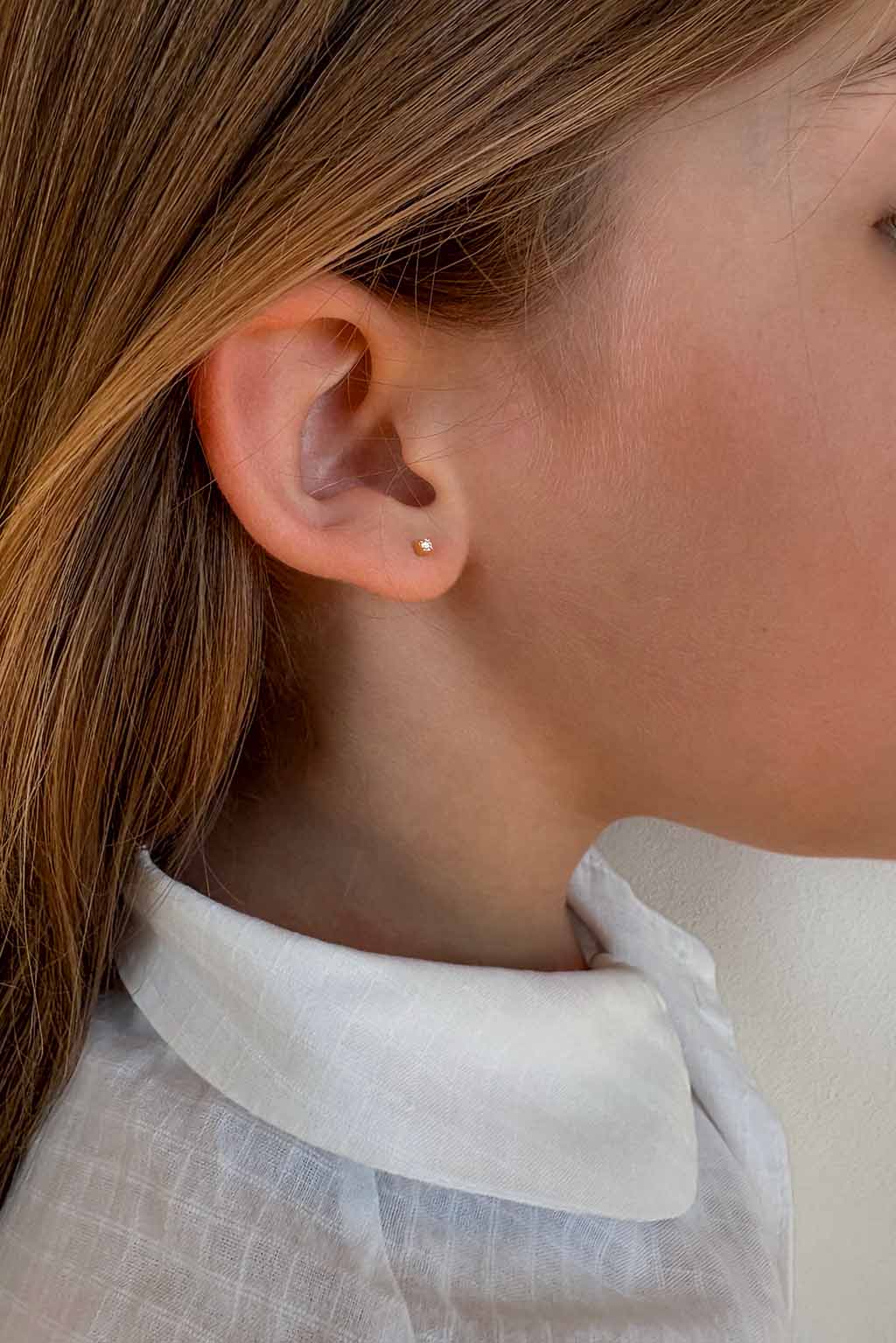 Blond child wearing a single Baby Box 1'7 earring in 18k yellow gold with diamonds by Sansoeurs, visible on one ear.