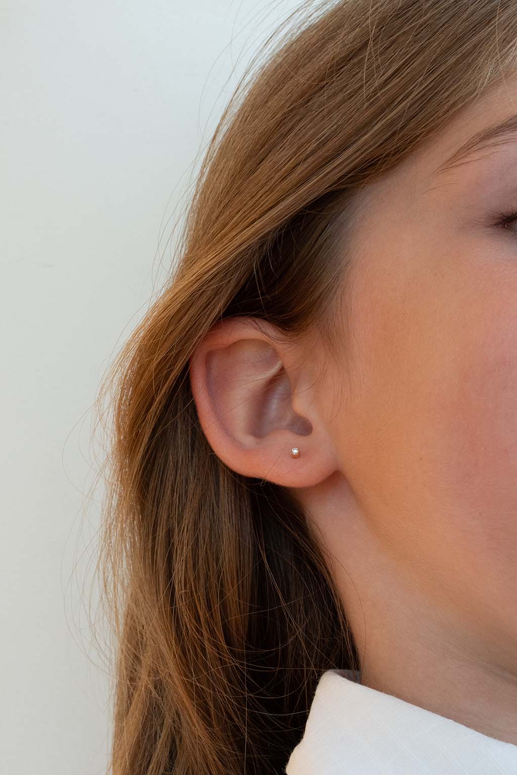 Blond child wearing a single Baby Box earring in 18k yellow gold with diamonds by Sansoeurs, visible on one ear.