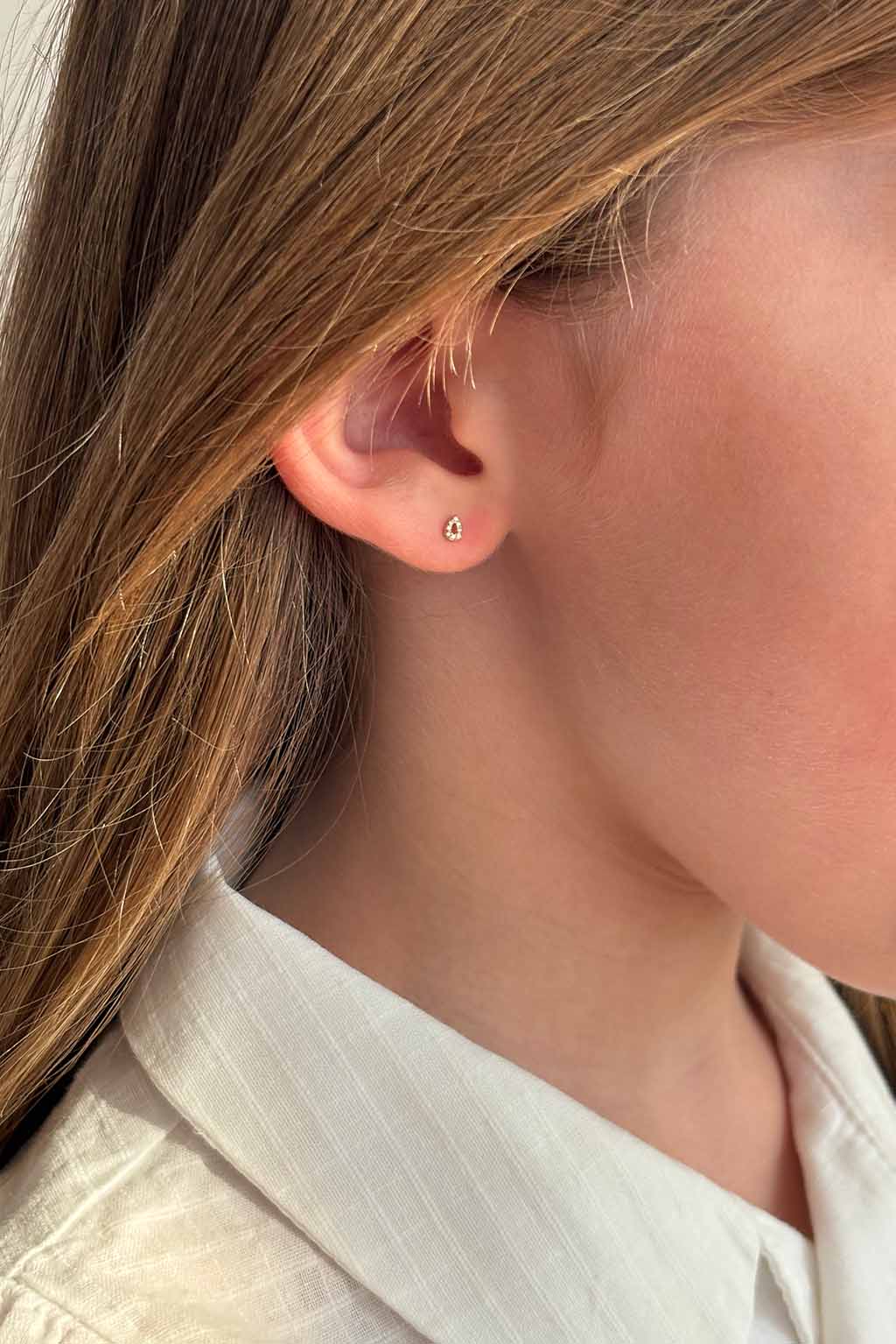 Blond child wearing a single Baby Bubbles earring in 18k yellow gold with diamonds by Sansoeurs, visible on one ear.