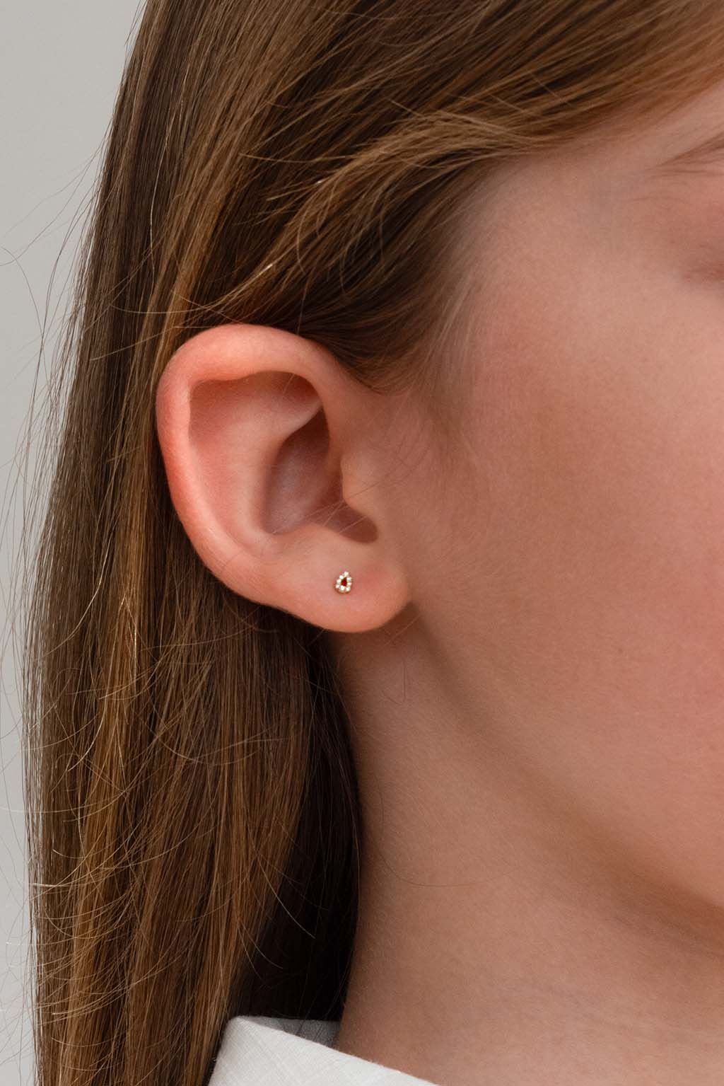 Blond child wearing a single Baby Bubbles earring in 18k yellow gold with diamonds by Sansoeurs, visible on one ear.