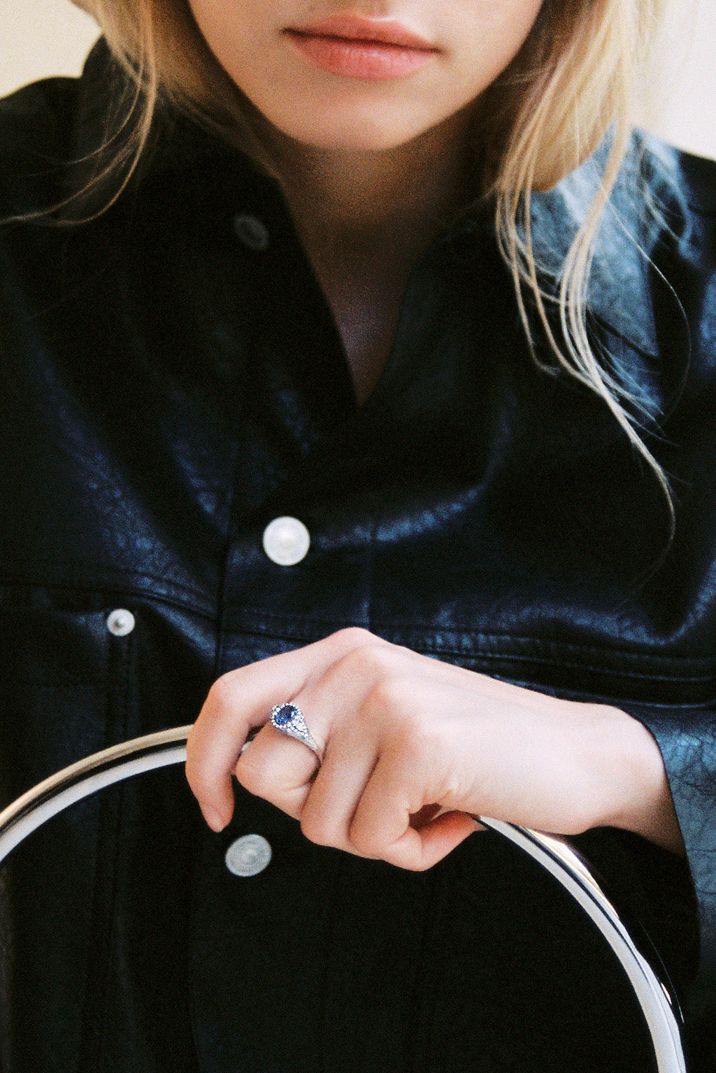 Portrait of a blonde woman with the signet sapphire white 18k gokd ring with diamonds sitting in a chair