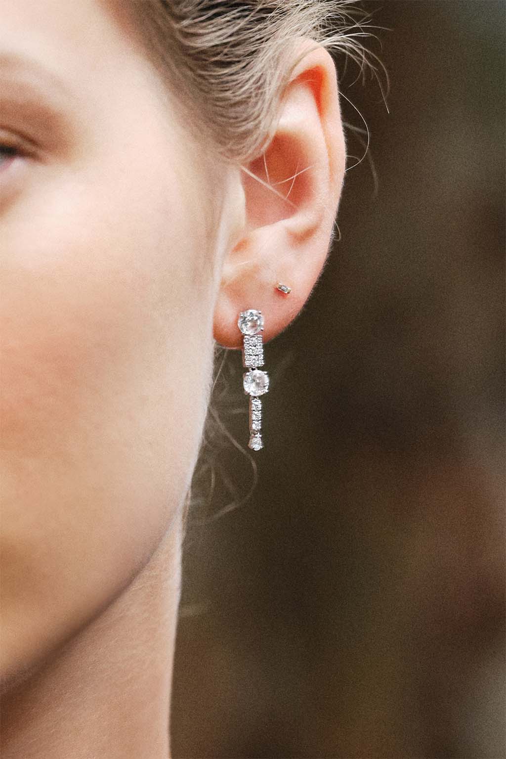 Model wearing the 18k white gold Long Wife Topaz earring with topaz and G VS diamonds by Sansoeurs.