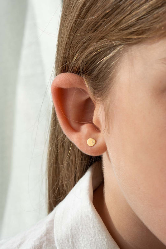 Blond child wearing a single Baby Dots earring in 18k yellow gold with three diamonds by Sansoeurs, visible on one ear.