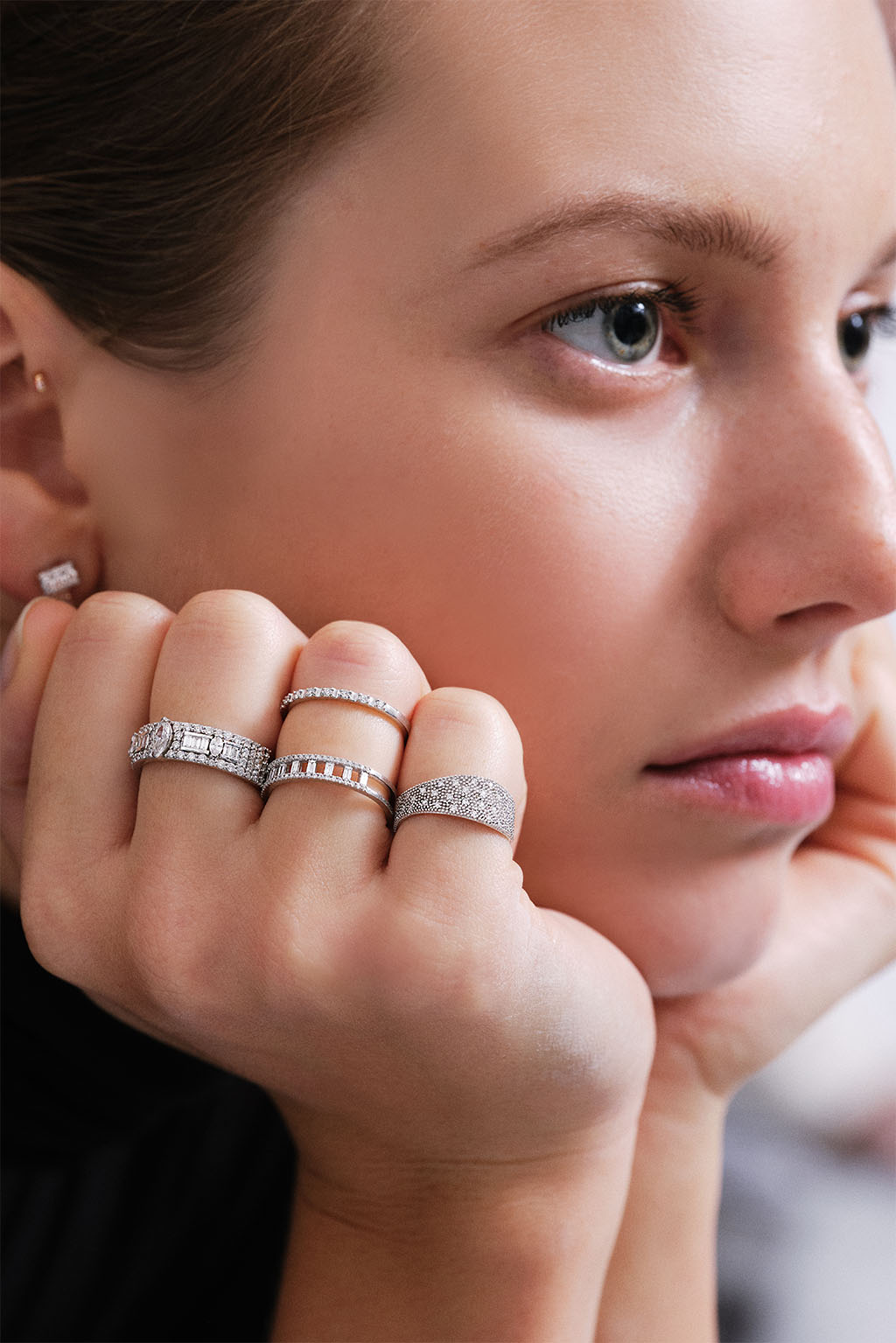Portrait of model showing her hand wearing the Irregular Band Diamonds ring in 18k white gold, paired with the Spectra ring and Second Wife Band, all fine jewelry by Sansoeurs