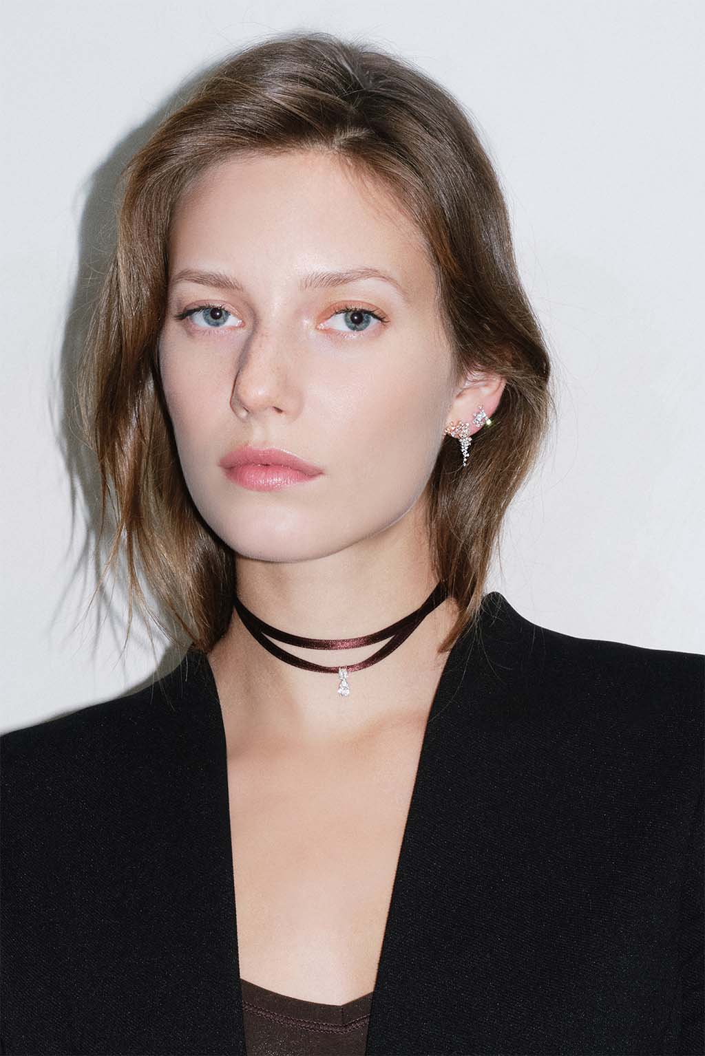 Model portrait wearing 18k gold Big Cascade earrings paired with the Star Cascade earring, both diamond fine jewelry pieces by Sansoeurs.