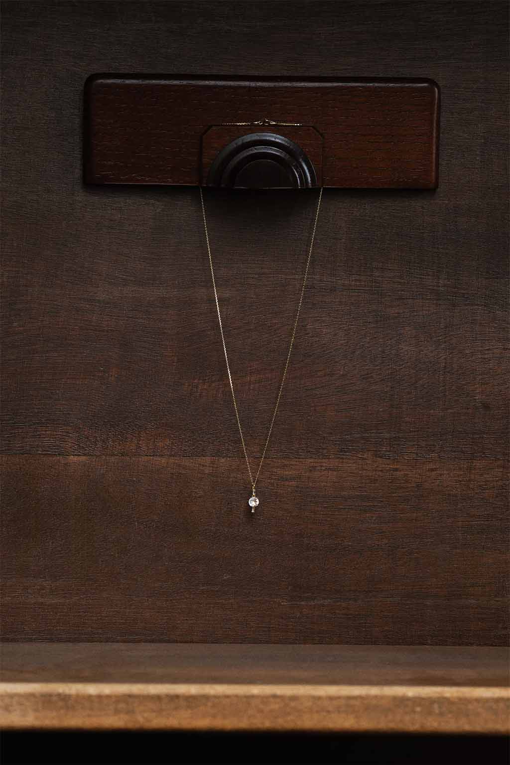 18k gold topaz necklace from Sansoeurs hanging from a minimalist wooden jewelry stand.