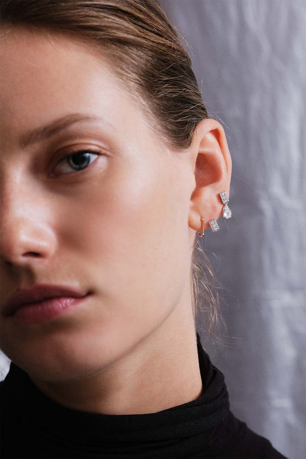 Model wearing the 18k white gold Wife Topaz earring by Sansoeurs, paired with the Plaque Diamonds gold earring.”